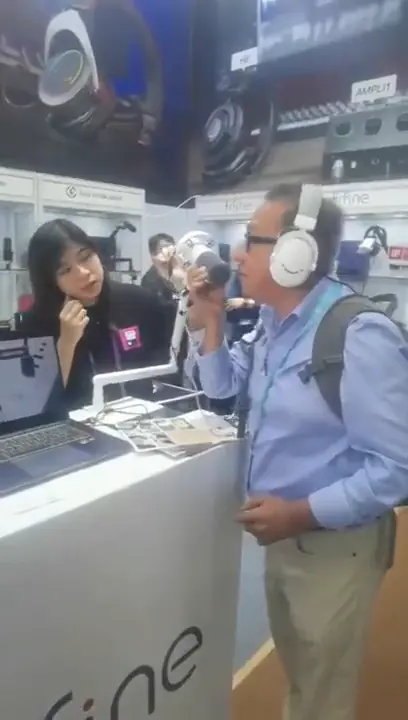 Asesor probando audífonos junto a la expositora del stand